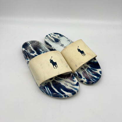 Pair of blue and white patterned slides with a brand logo on a light gray background