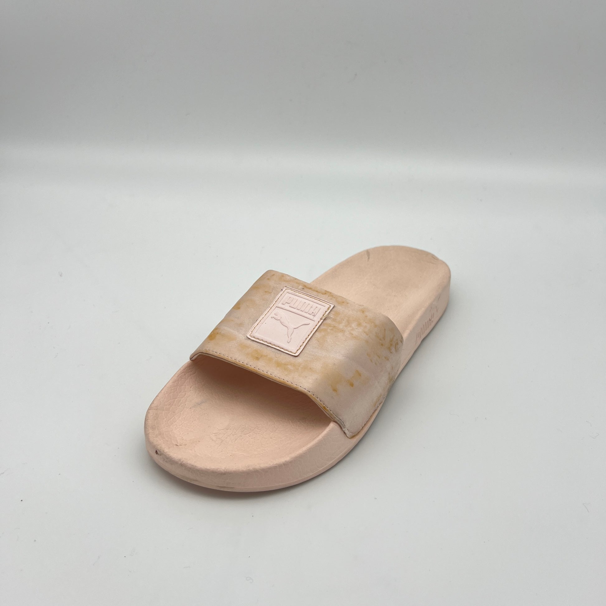 Beige slide sandal with a brand logo on a light gray background