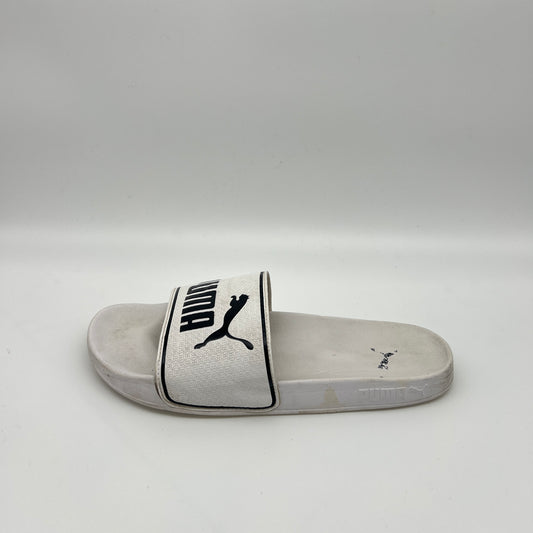 Side view of a white Puma Leadcat 2.0 slide sandal featuring a padded strap with a black Puma cat logo and text, set against a white contoured footbed.