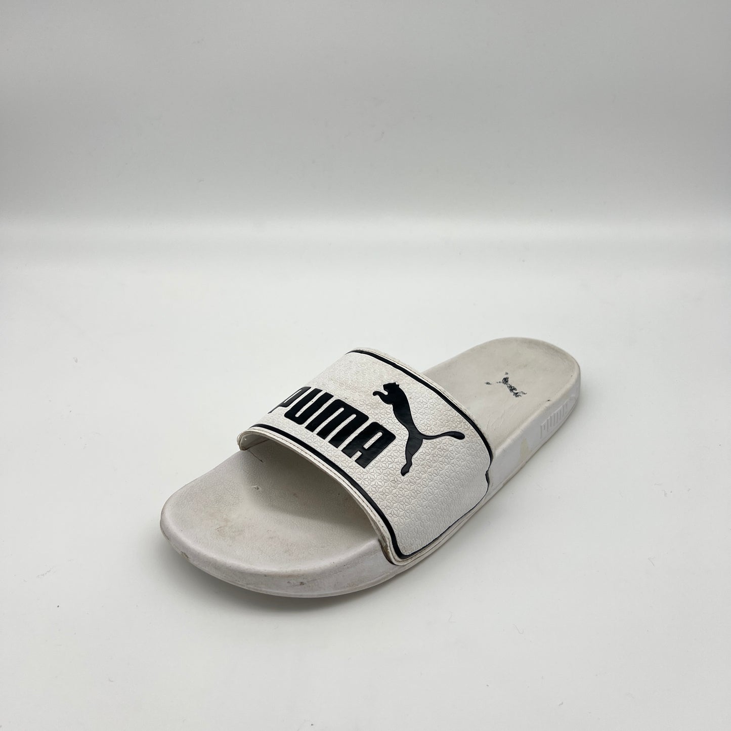 White slide sandal with Puma logo on a light gray background