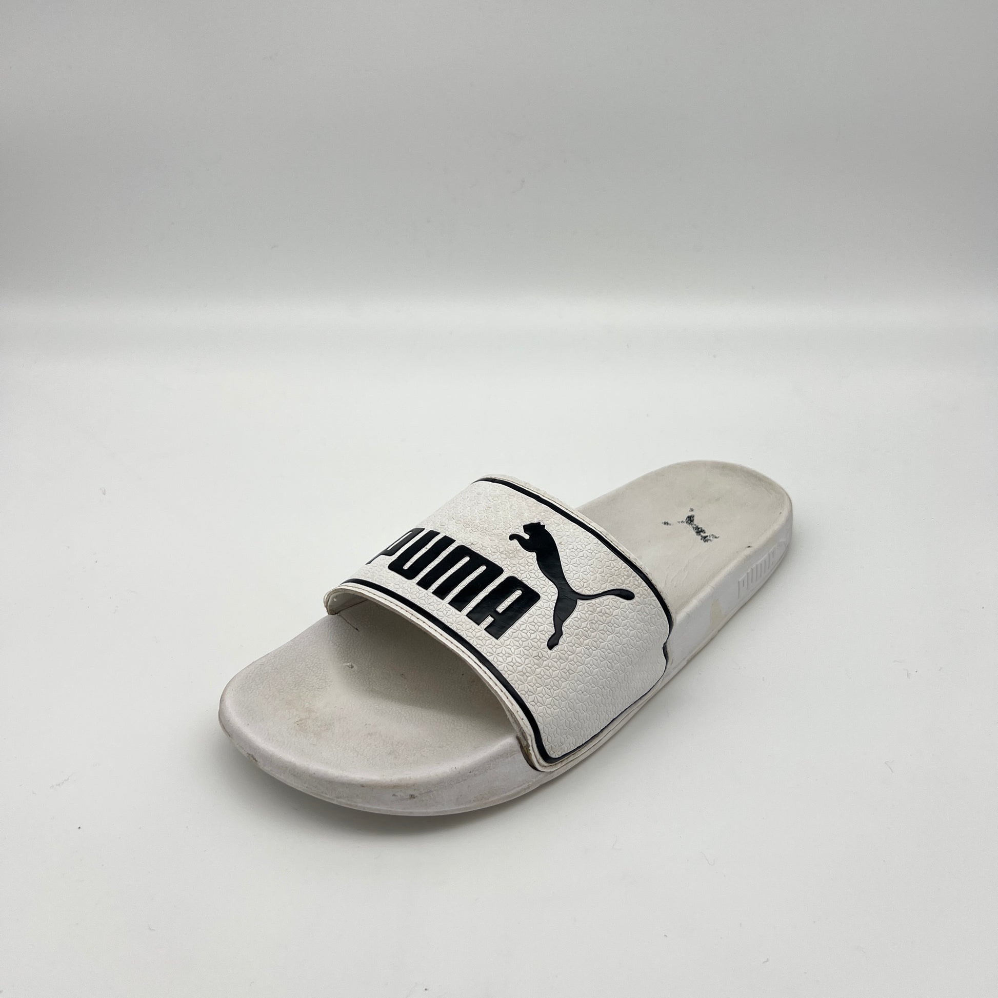 White slide sandal with Puma logo on a light gray background