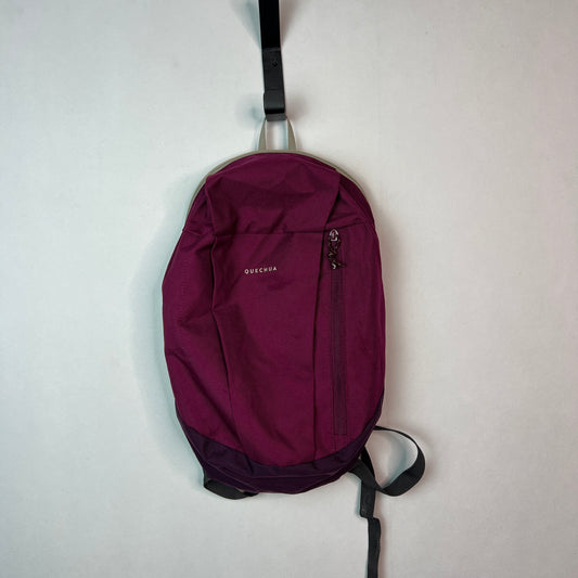Purple Quechua NH100 10L hiking backpack hanging on a wall hook