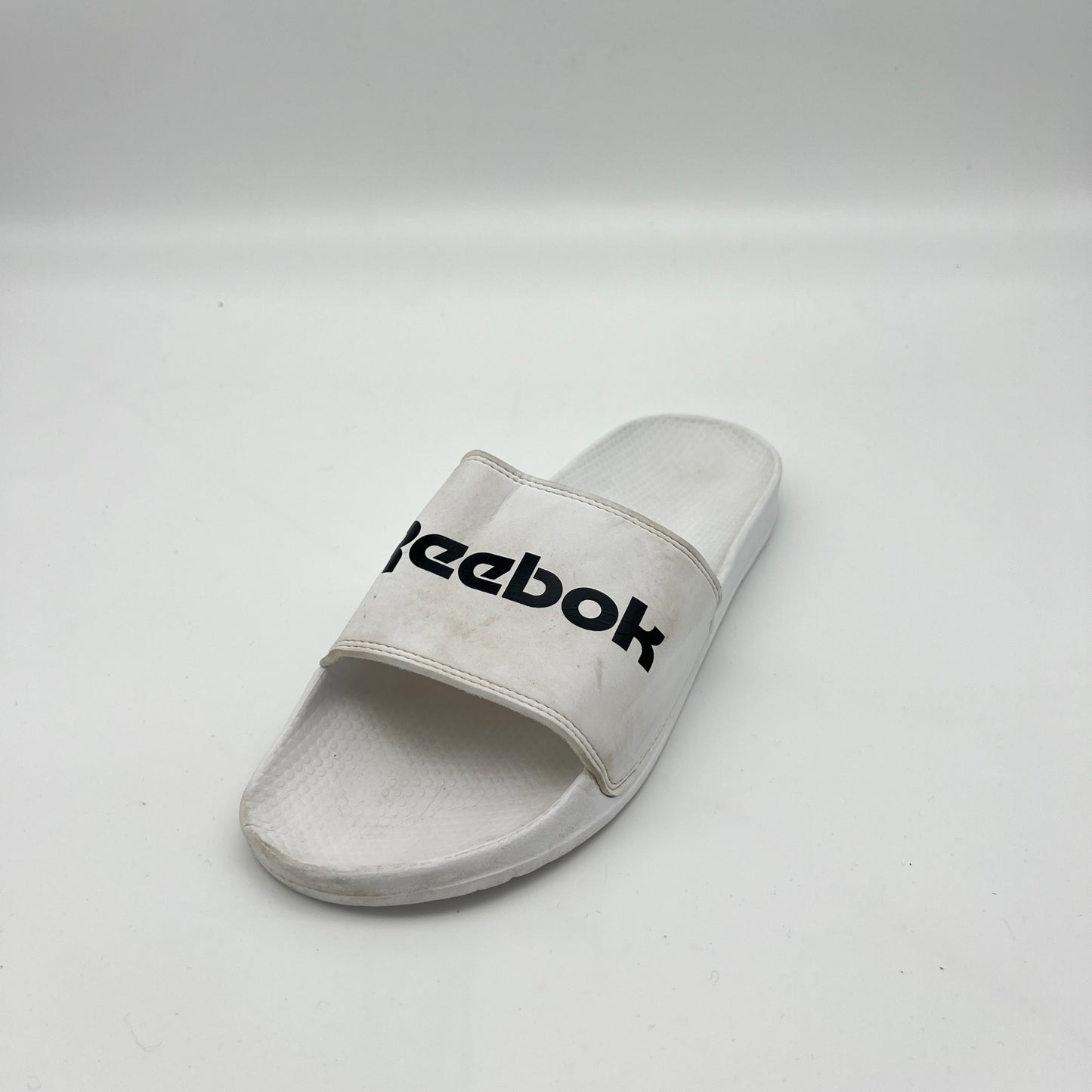 White Reebok slide sandal on a light gray background