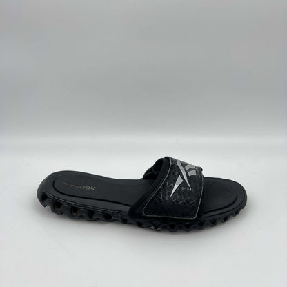 Reebok Zig Nano Slide black and silver athletic sandal with zigzag cushioning sole and adjustable logo strap.