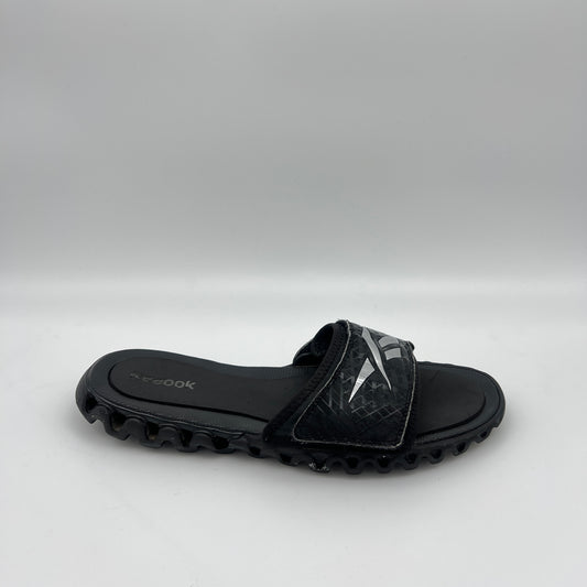 Reebok Zig Nano Slide black and silver athletic sandal with zigzag cushioning sole and adjustable logo strap.
