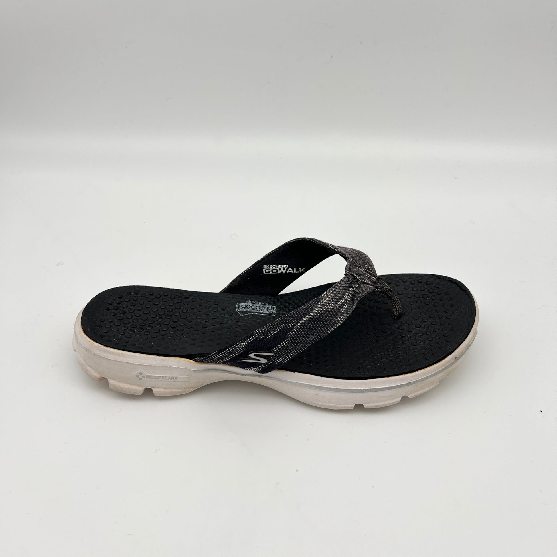 Side view of a black Skechers GOwalk 3 thong-style flip flop with a textured "Goga Mat" footbed, grey patterned fabric straps, and a thick white cushioned sole.