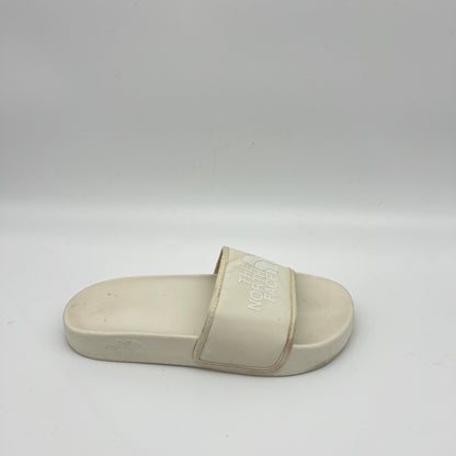 Side view of an off-white The North Face Base Camp Slide III with a textured "THE NORTH FACE" logo on a wide synthetic strap and a contoured cream footbed.