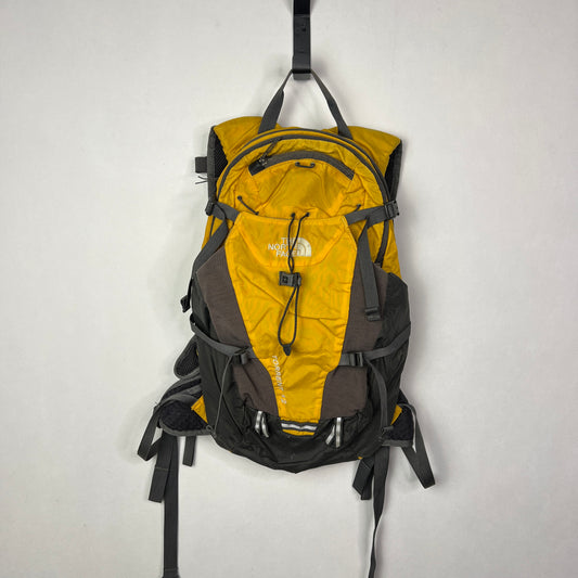 Front view of a yellow and black The North Face Torrent 12 backpack with a front bungee cord, compression straps, and reflective safety tabs