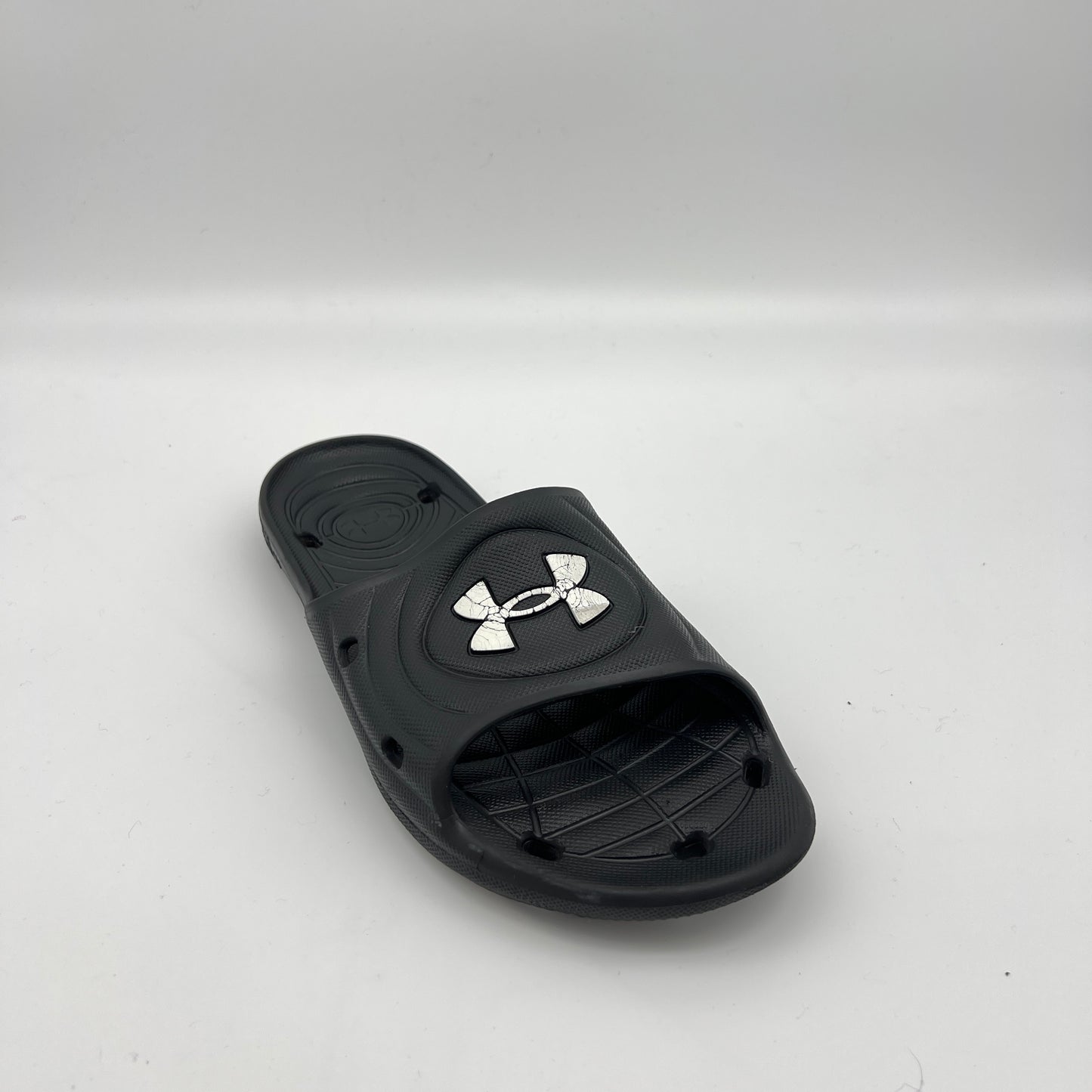 Side view of black Under Armour Locker IV sport slides featuring drainage holes in the sole and strap.