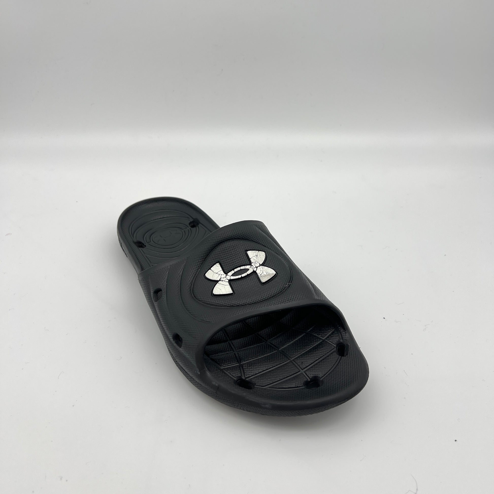 Side view of black Under Armour Locker IV sport slides featuring drainage holes in the sole and strap.