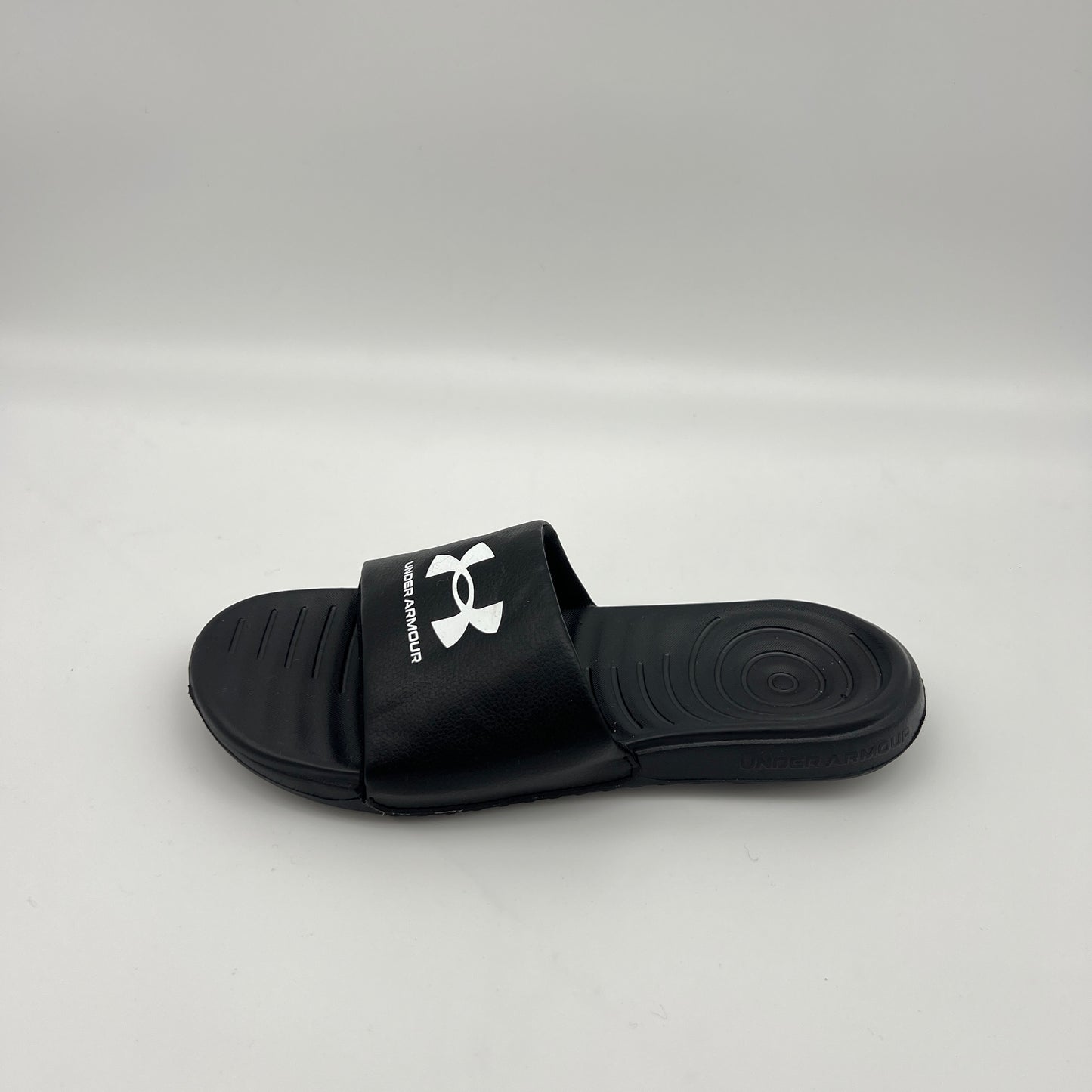 Side view of Under Armour Men's Ignite VI slide sandal in black and white with a contoured footbed