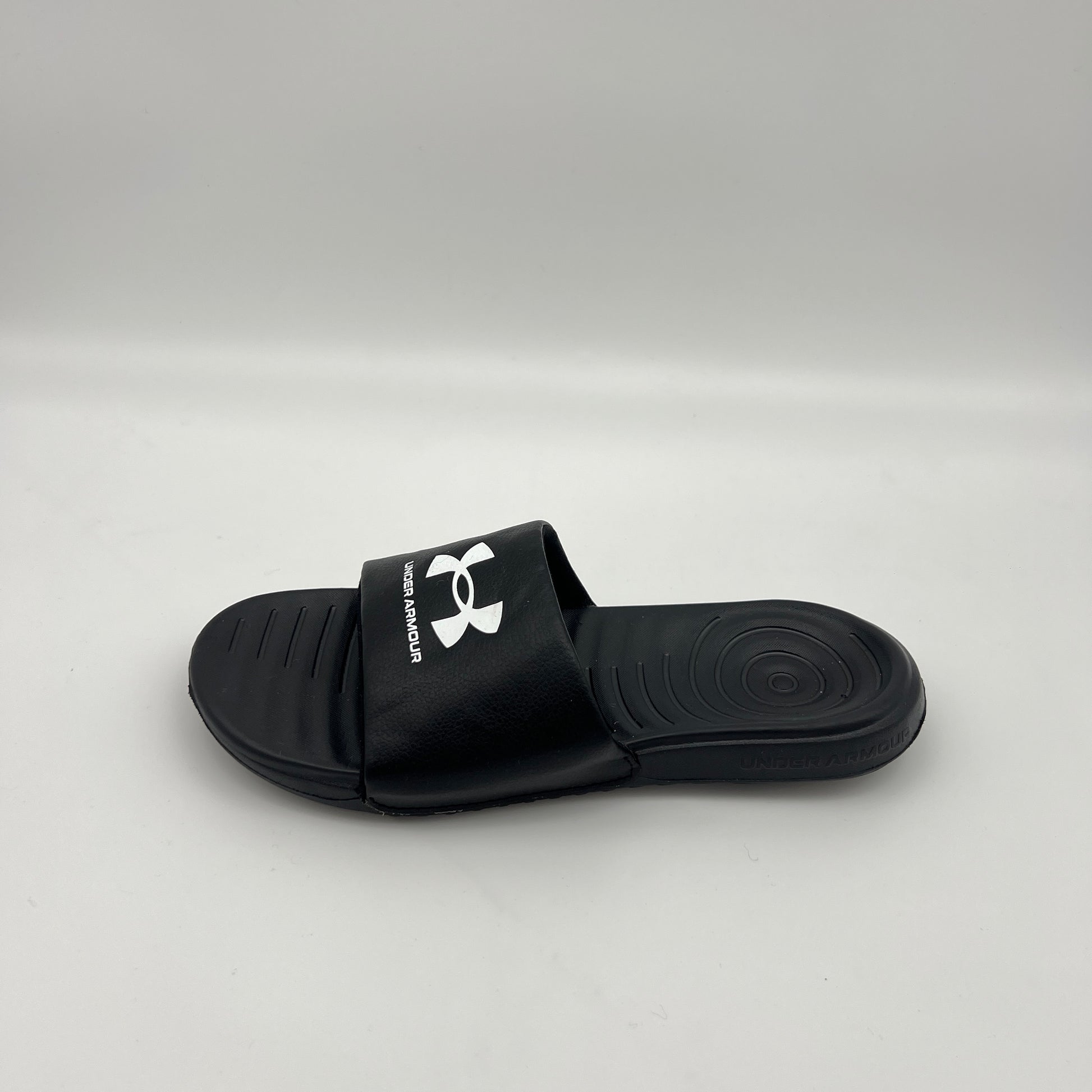 Side view of Under Armour Men's Ignite VI slide sandal in black and white with a contoured footbed