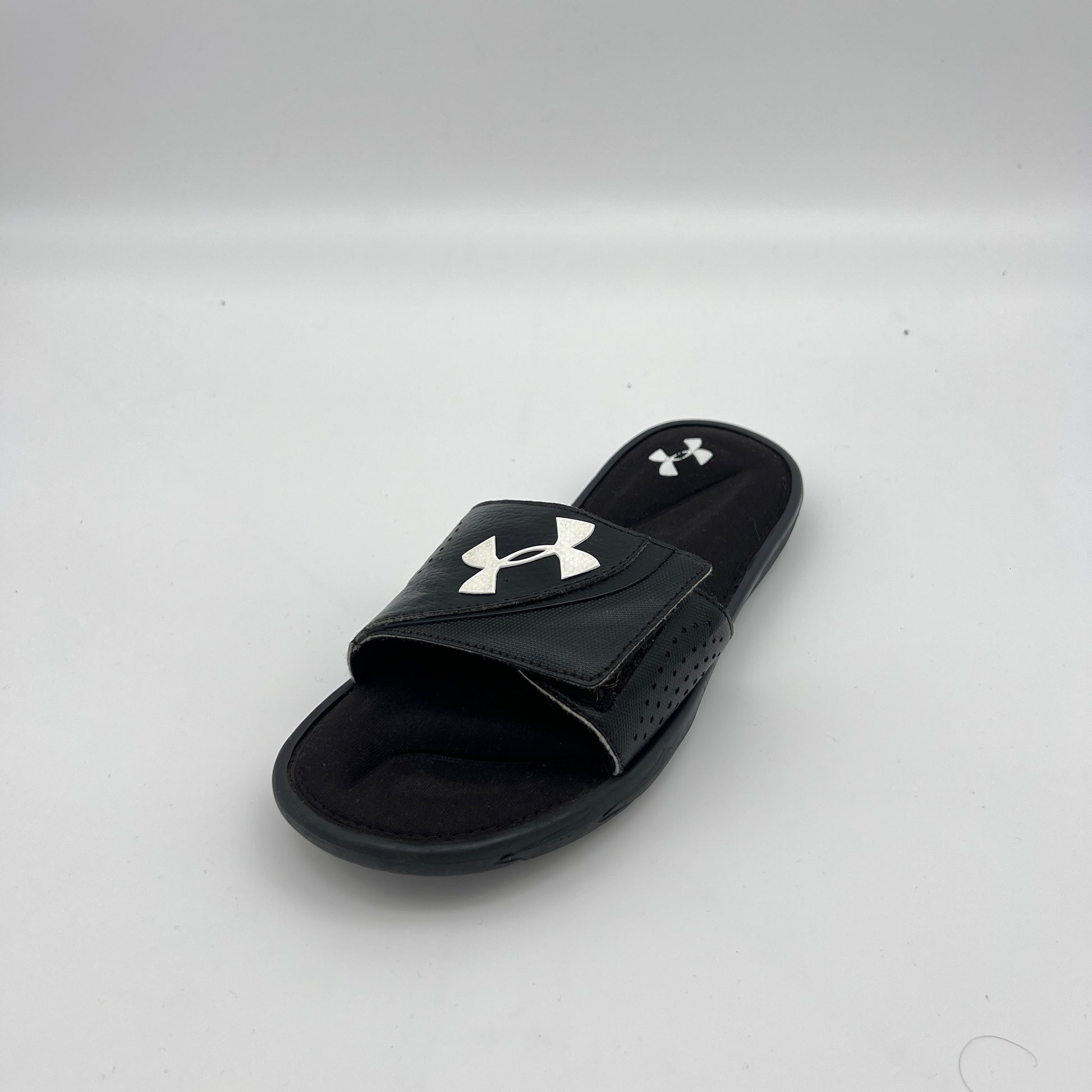 Under Armour athletic slides featuring an adjustable logo strap and plush memory foam cushioning