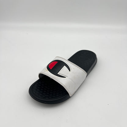 White slide sandal with black sole and red and black logo on a light gray background
