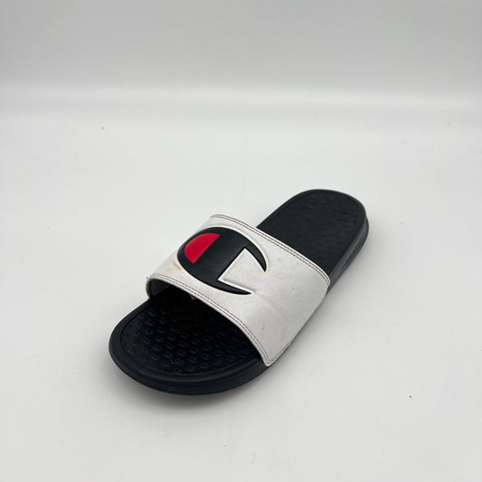 White slide sandal with black sole and red and black logo on a light gray background