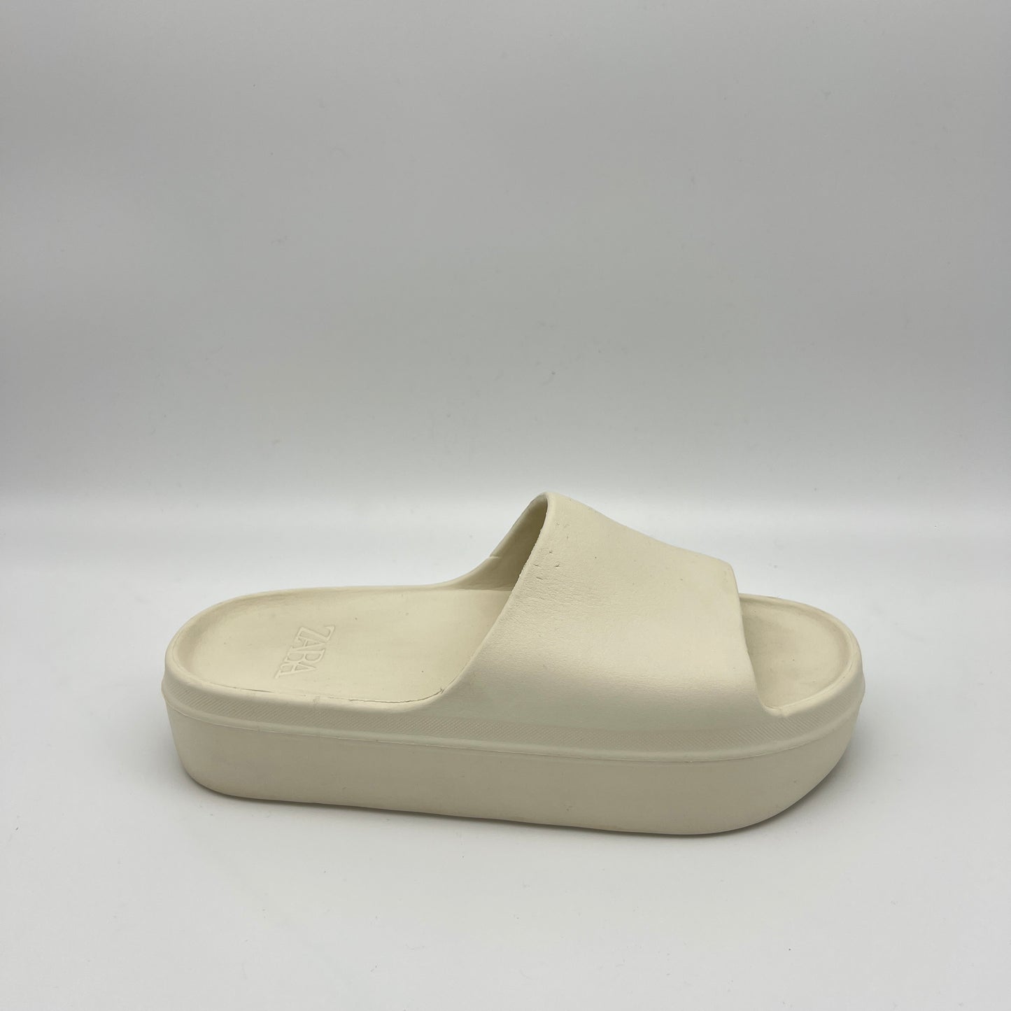 A pair of chunky ivory Zara rubberized platform slides on a neutral background, featuring a thick sole and wide single strap for a minimalist look.