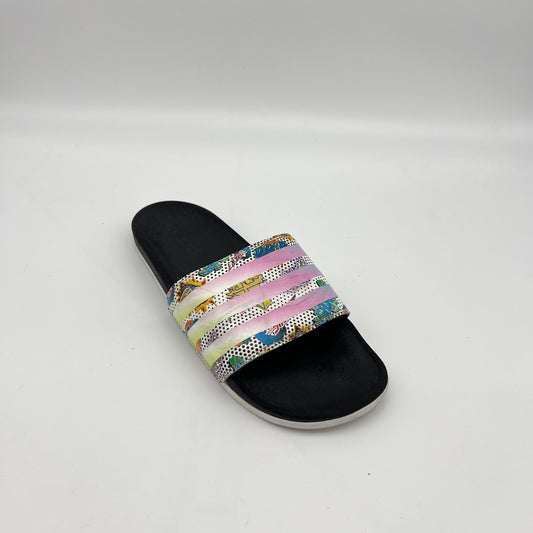 A close-up of the pop-art comic strip pattern and reflective 3-Stripes on the bandage strap of an Adidas Adilette slide.