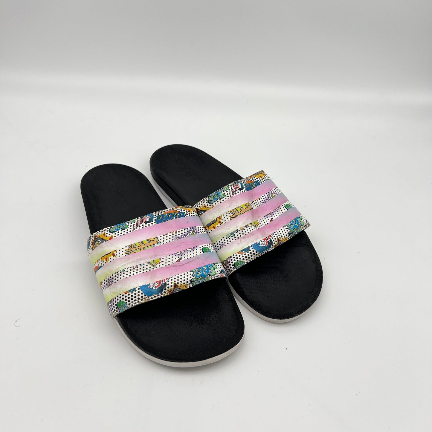 Top-down view of the black contoured Cloudfoam Plus footbed and synthetic strap of the Adidas "Comics" edition slide