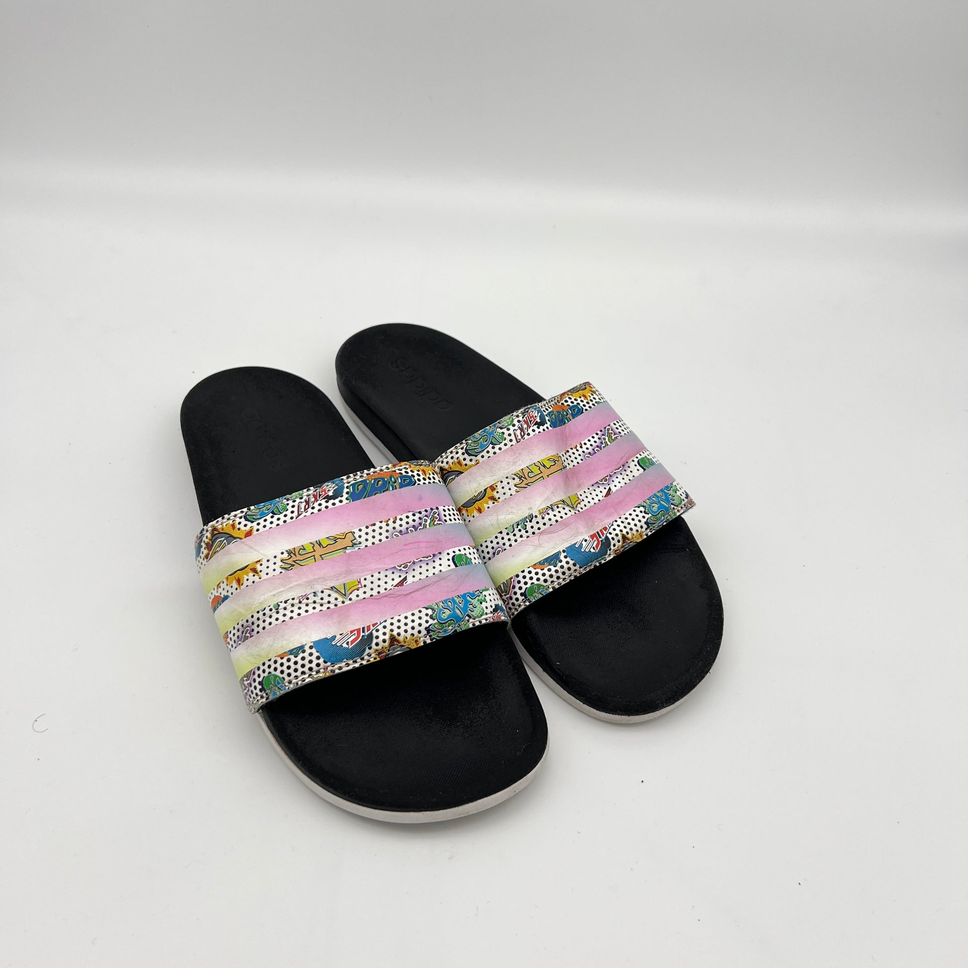 Top-down view of the black contoured Cloudfoam Plus footbed and synthetic strap of the Adidas "Comics" edition slide