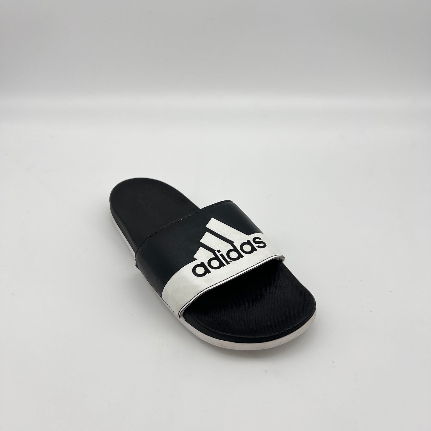 Black and white Adidas slide sandal on a light gray background
