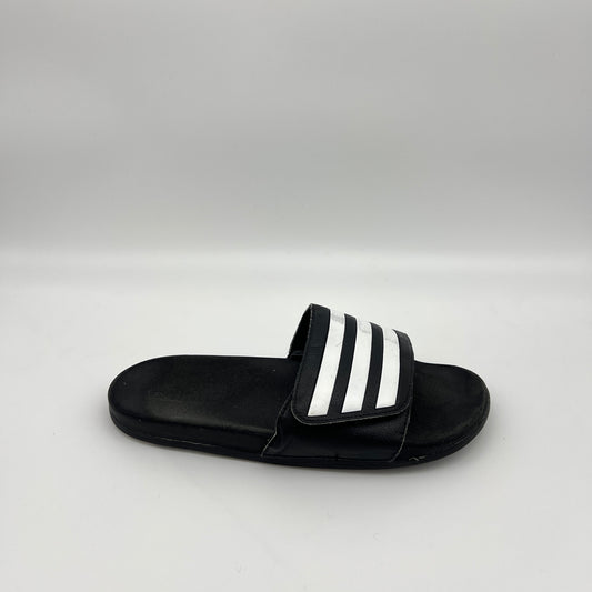 Side profile of a single black adidas Adilette slide sandal with three white iconic stripes on the strap and a smooth footbed on a plain white background.