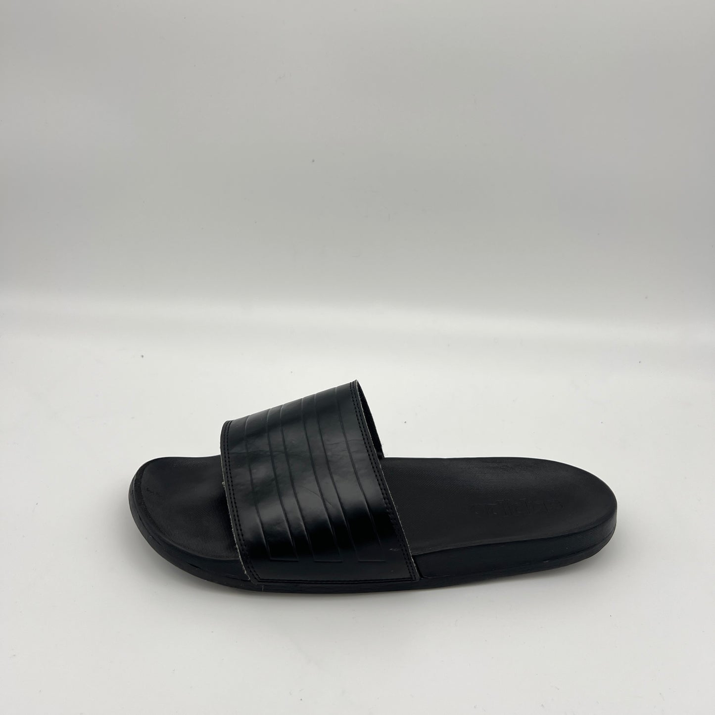 Side view of adidas Adilette Comfort slides in all-black with a textured bandage strap.