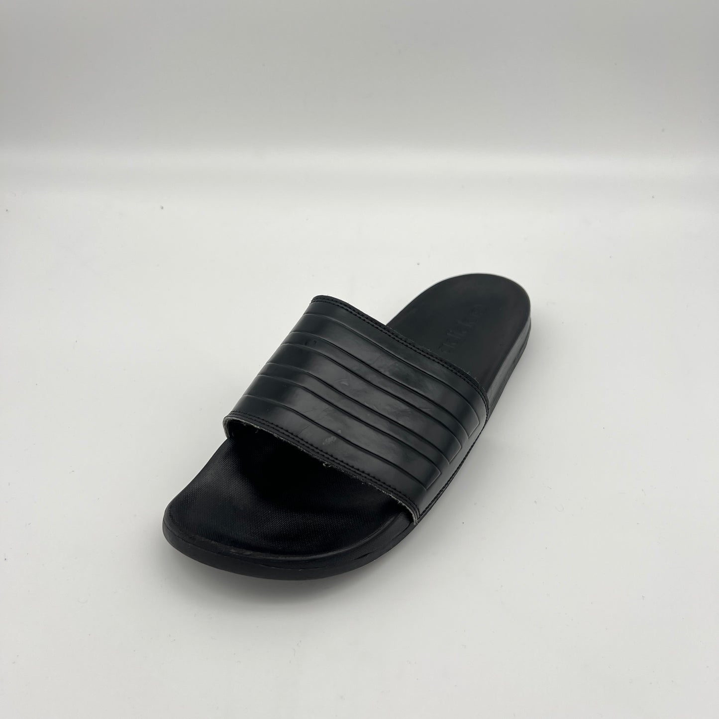  Monochromatic black adidas athletic slides featuring a cushioned Cloudfoam footbed.