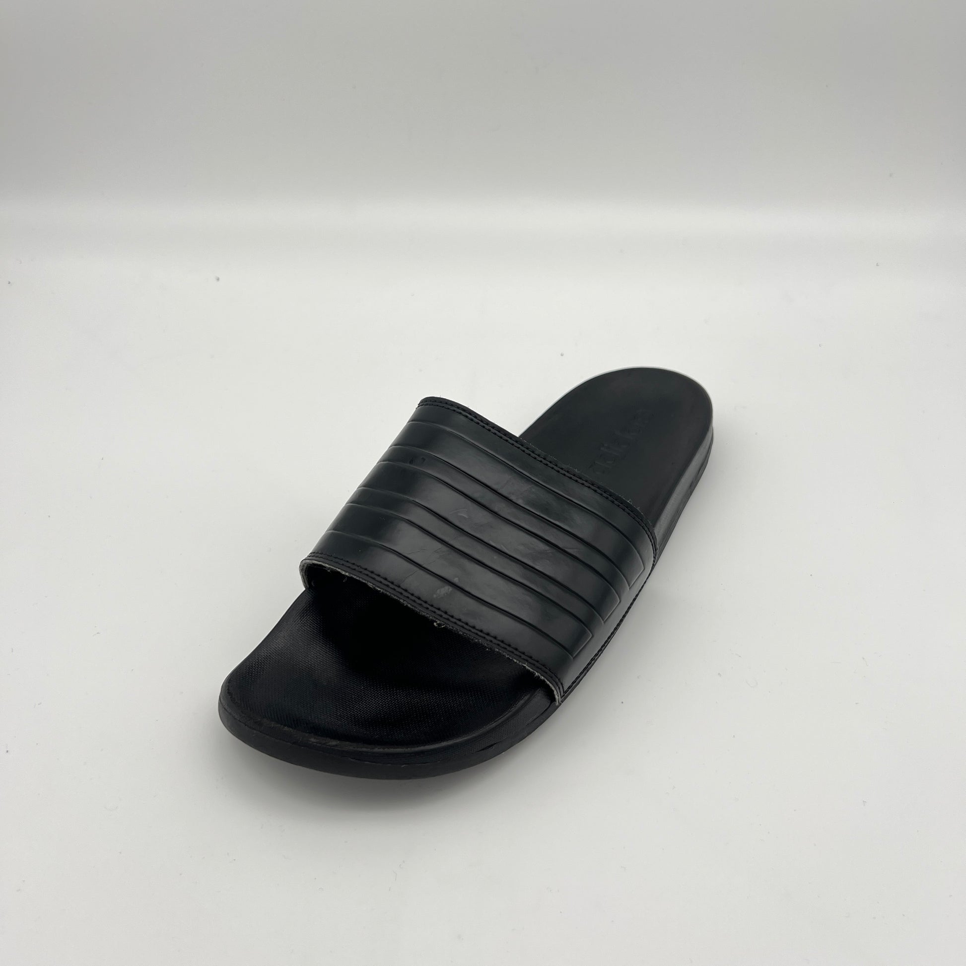  Monochromatic black adidas athletic slides featuring a cushioned Cloudfoam footbed.
