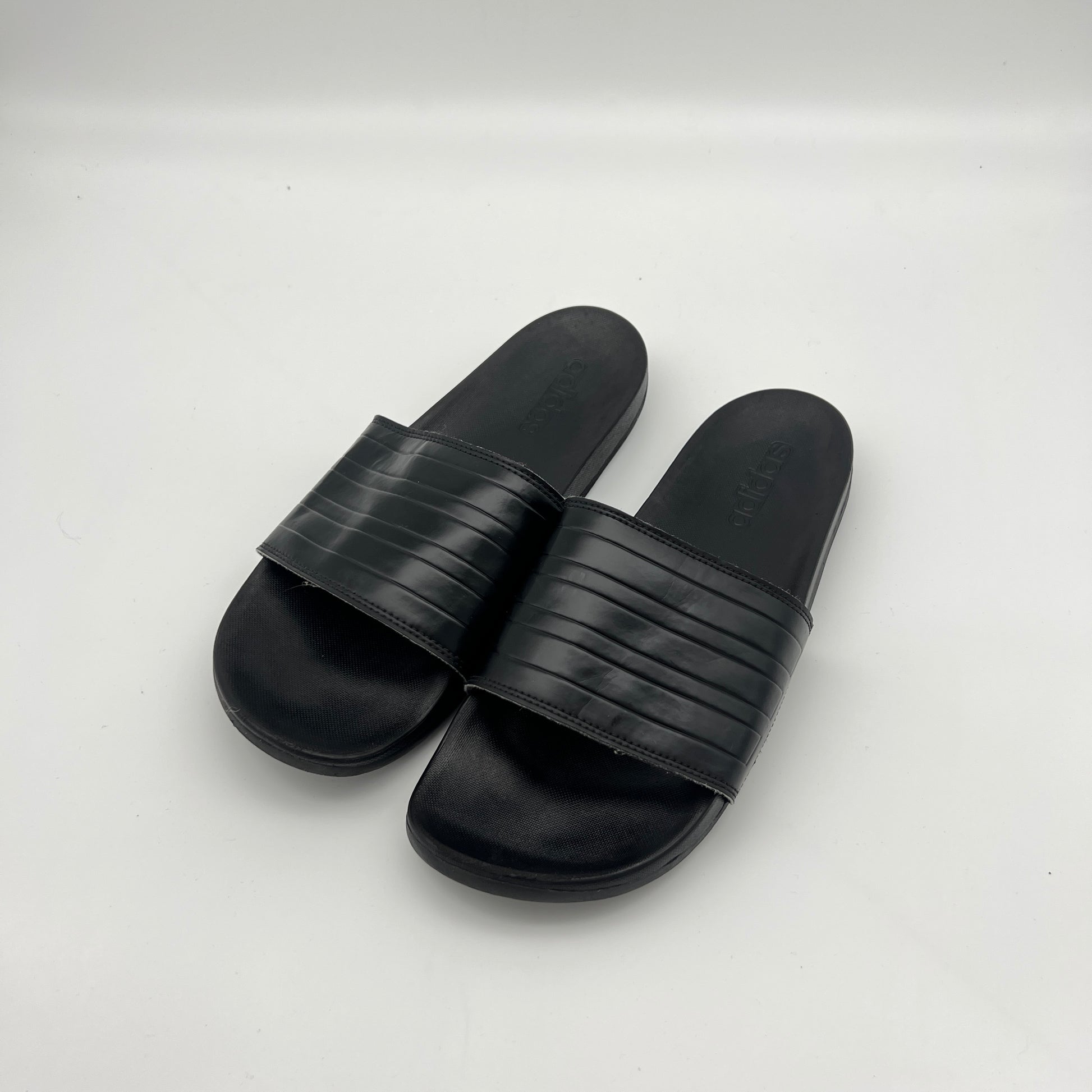 Lightweight adidas Adilette sandals with a contoured sole and signature three-stripe branding.