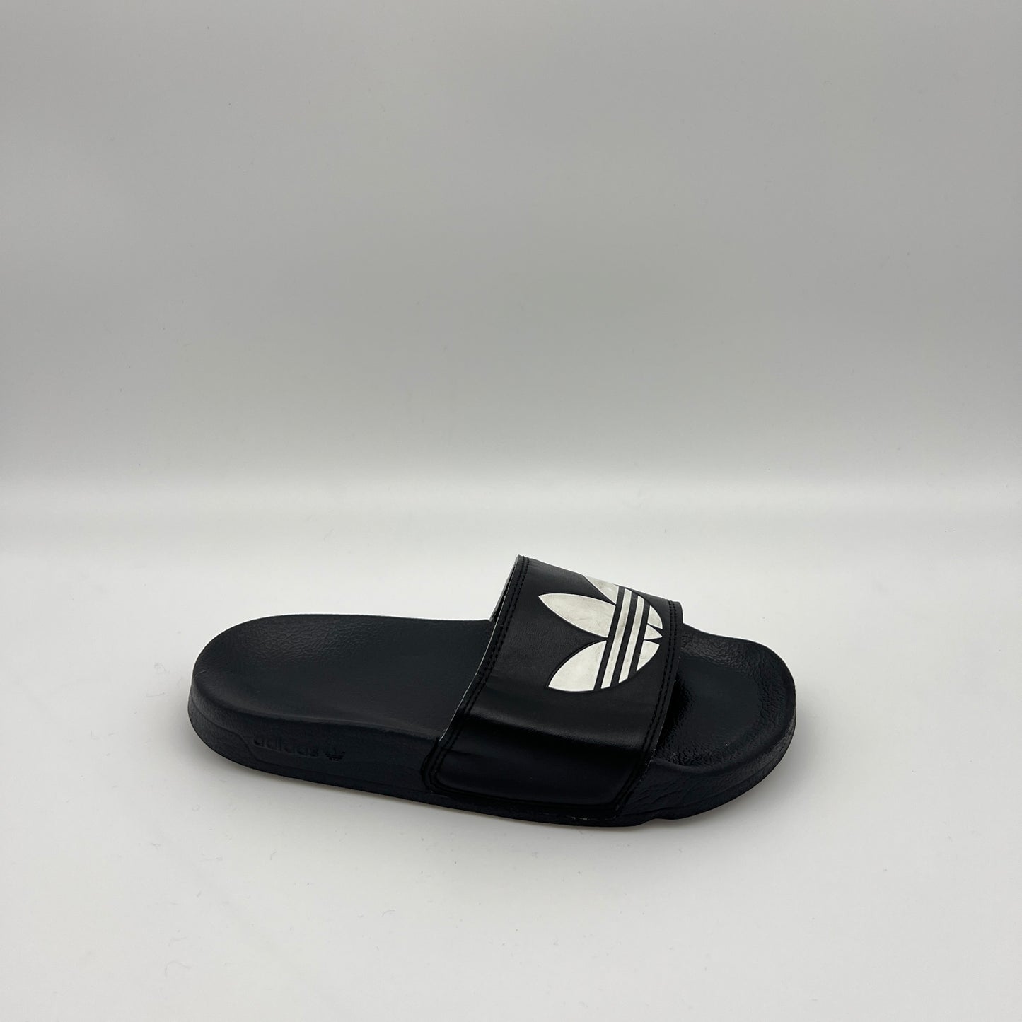 adidas Adilette Lite slide in black featuring a large white Trefoil logo on the strap and a contoured, cushioned black footbed.