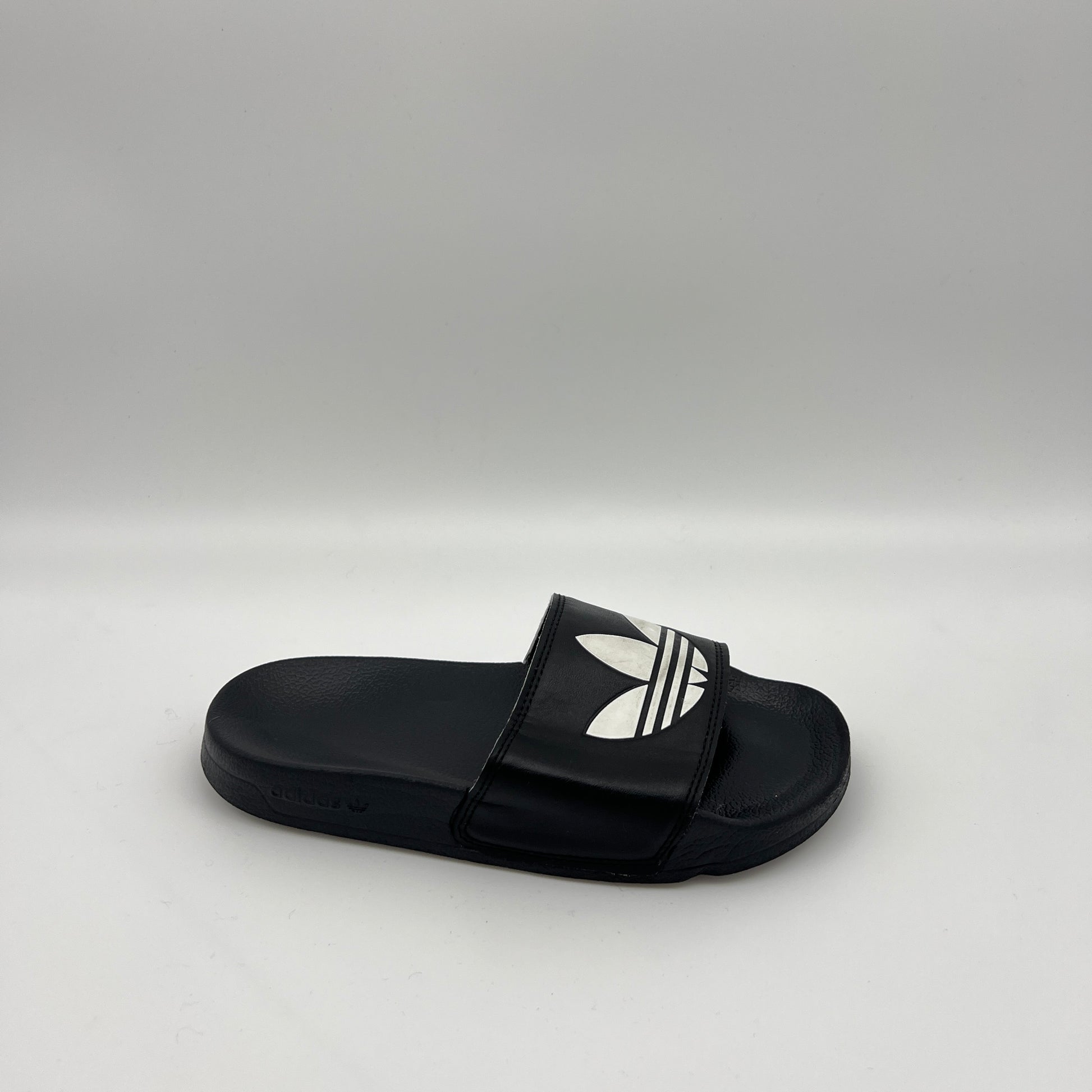 adidas Adilette Lite slide in black featuring a large white Trefoil logo on the strap and a contoured, cushioned black footbed.