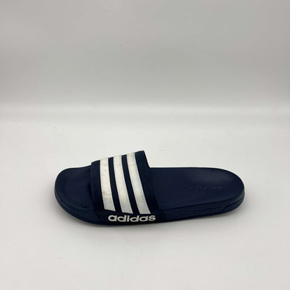 Side profile of a navy blue adidas Adilette Shower slide sandal with white iconic stripes on the strap and a textured footbed on a white background.
