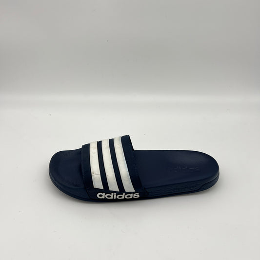 Side profile of a navy blue adidas Adilette Shower slide sandal with white iconic stripes on the strap and a textured footbed on a white background.
