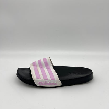 Side view of a white adidas Adilette Shower Slide with a black footbed and three light purple "Magic Lilac" stripes on the synthetic strap against a white background.