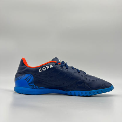Navy soccer shoe with blue sole and orange accents on a gray background