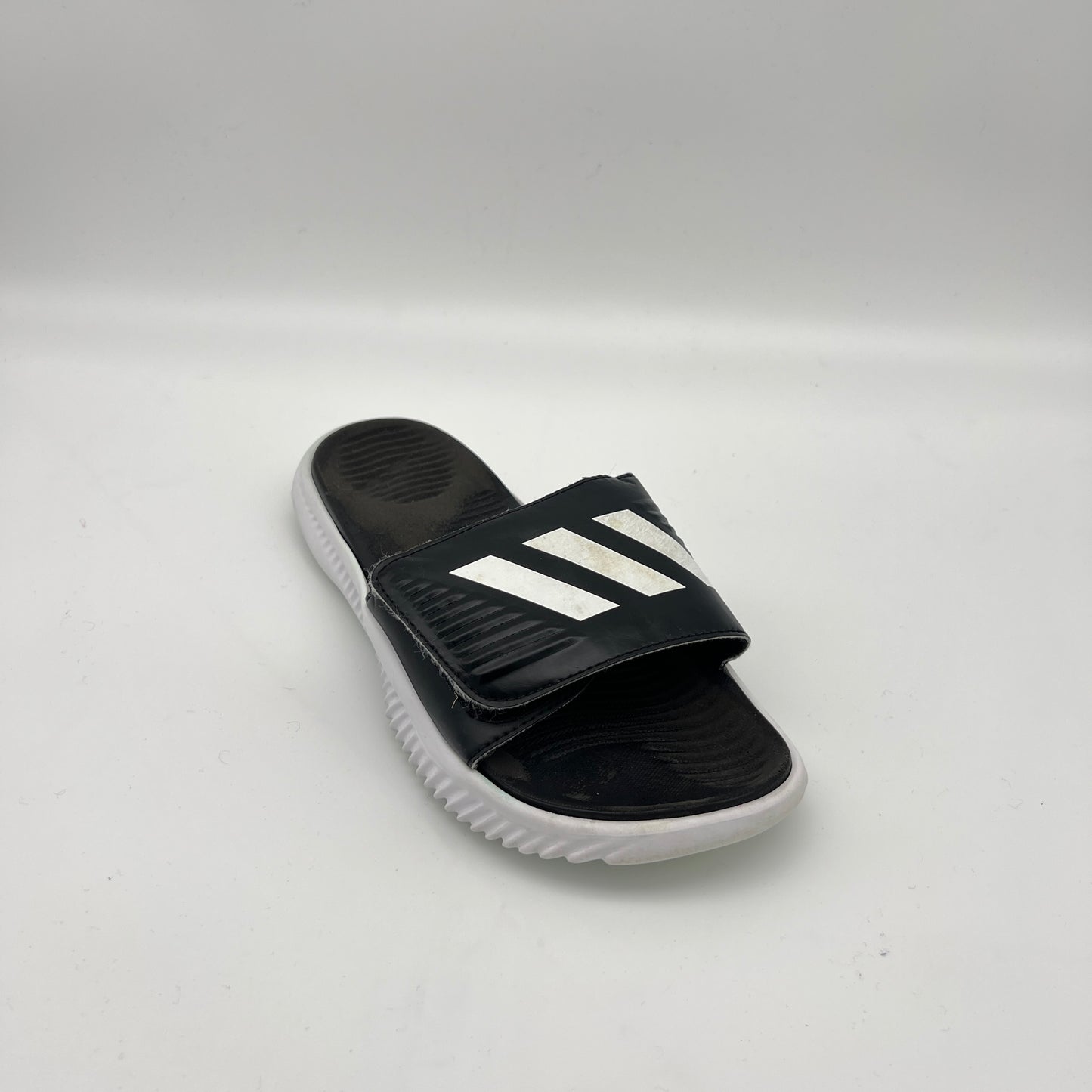 Black slide sandal with white stripes on a light gray background