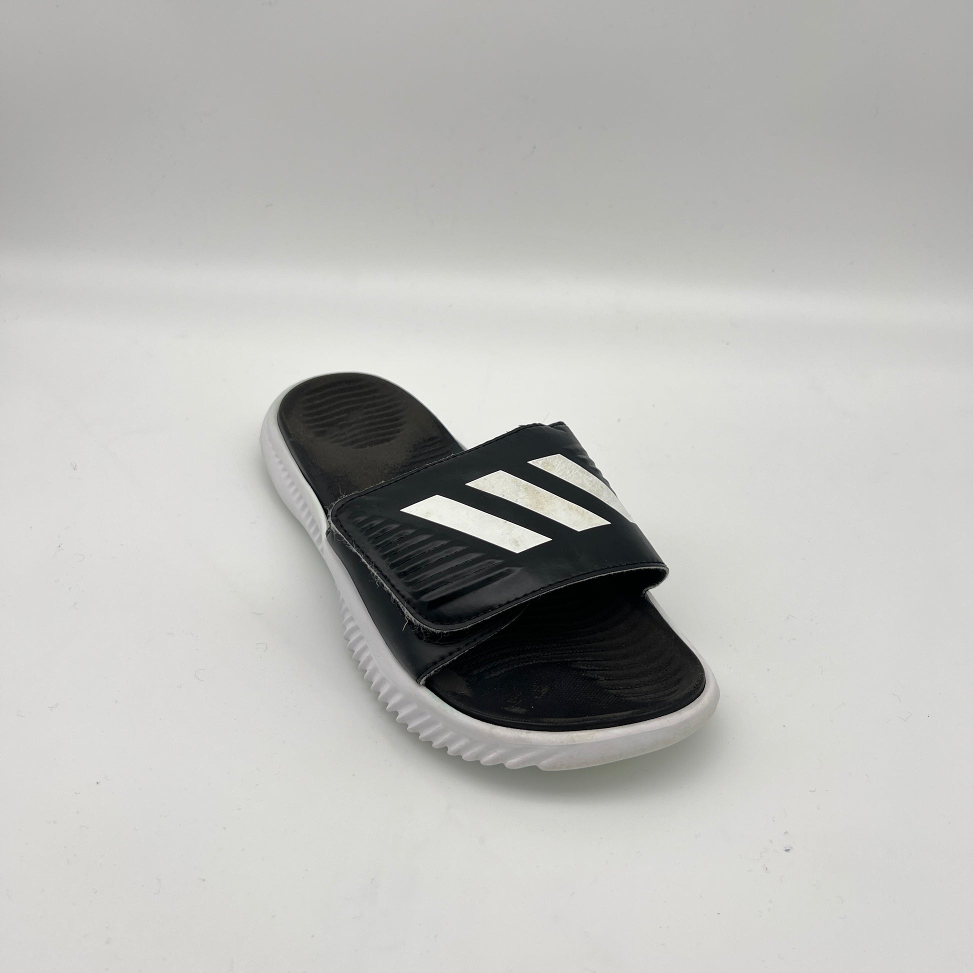 Black slide sandal with white stripes on a light gray background