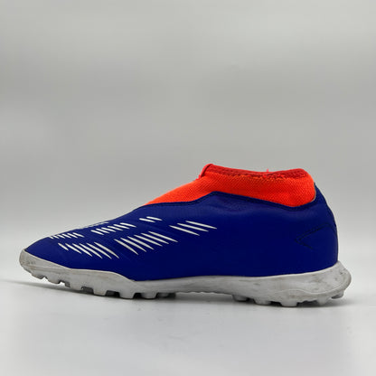 Side view of an adidas Predator League laceless turf soccer boot in lucid blue, footwear white, and solar red with a white lugged rubber outsole.