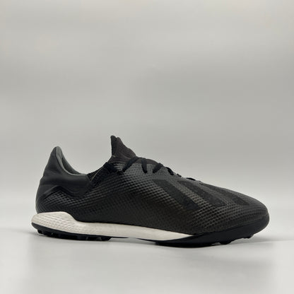 Side profile of a core black adidas X Tango 18.3 TF turf soccer shoe with a white midsole and black studded outsole for synthetic surfaces.
