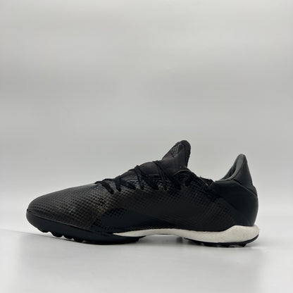 Side profile of a core black adidas X Tango 18.3 TF turf soccer shoe with a white midsole and black studded outsole for synthetic surfaces.
