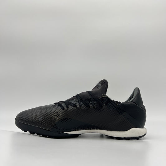 Side profile of a core black adidas X Tango 18.3 TF turf soccer shoe with a white midsole and black studded outsole for synthetic surfaces.
